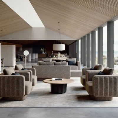 Sabree Italian modern furniture design collection: sofas, armchairs and coffee table in greige bouclé fabric in a resort lounge with wooden ceiling and seaside view — Frezza
