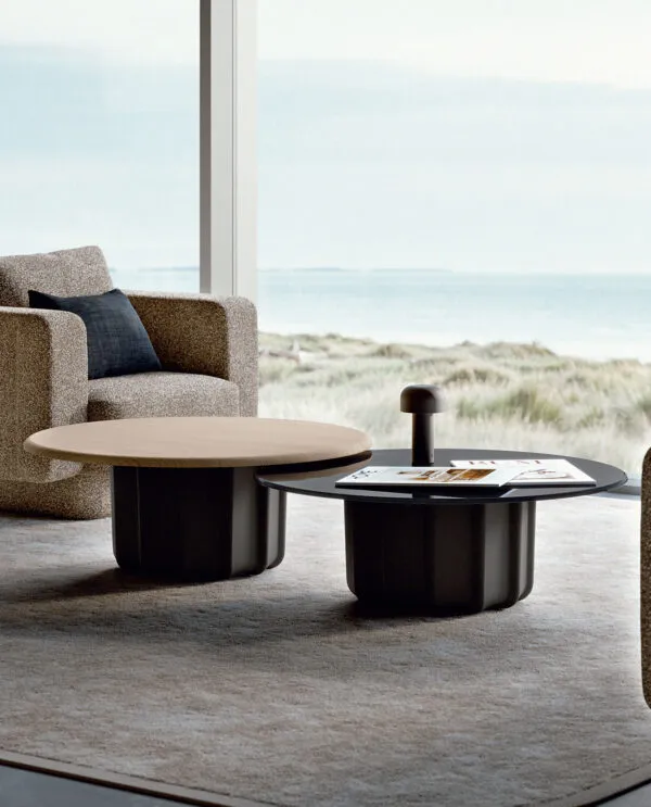 Table basse design italien Sabree, base sculptural noire et plateau chêne, dans un living côtier avec vue sur les dunes — design contemporain
