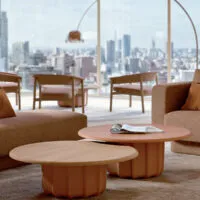 Tavolini da caffè di design Sabree in due misure accostate, finitura terracotta e top rovere, in uno spazio lounge di lusso con vista skyline — design italiano