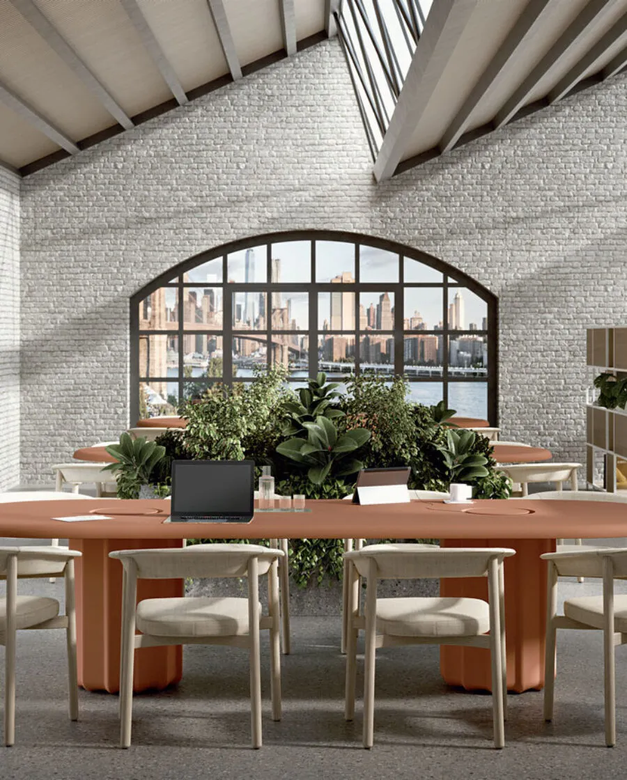 Table ovale design Sabree avec pieds centraux terracotta et chaises Lash dans un open space avec briques apparentes et fenêtres en arc — Frezza contract