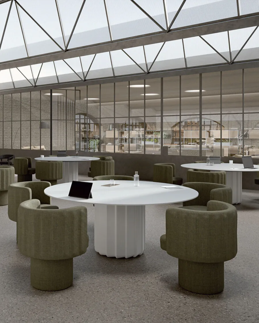Table ronde design Sabree à pied central avec plateau blanc dans un lounge open space avec fauteuils vert olive et parois vitrées — Frezza contract