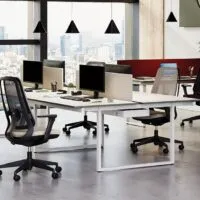 Sedia ufficio ergonomica professionale Areca nelle versioni Mesh e Fabric, in un open space con scrivanie bench e vista sulla città