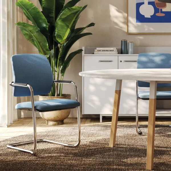 Collection Charlize, chaises de collectivité à piètement luge chromé, dossier et assise en tissu bleu, autour d'une table ronde