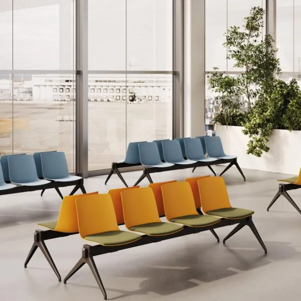 Panca sala d'attesa Yo Plastic Bench a 5 posti con sedute in polipropilene arancione, cuscino in tessuto verde e gambe a V rovesciata nere, in un'area d'attesa Frezza