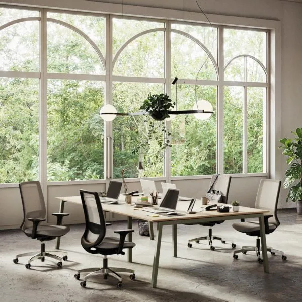 Sedie ergonomiche ufficio 8 ore Viggo in grigio con basi in nylon nero e alluminio lucido, attorno a un tavolo operativo condiviso davanti a grandi vetrate ad arco